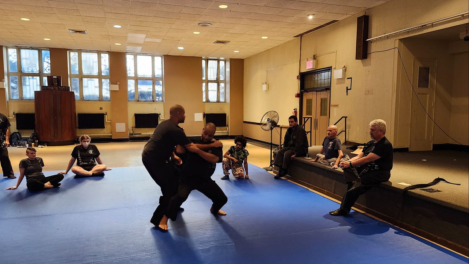 PJ Dixon teaching at the Muzosa Dojo's 30th anniversary seminar, with 2 teachers demonstrating his instructions.